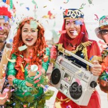 istockphoto-1368007541-1024×1024 Happy dressed people celebrating at carnival party throwing confetti - Focus on left girl hands